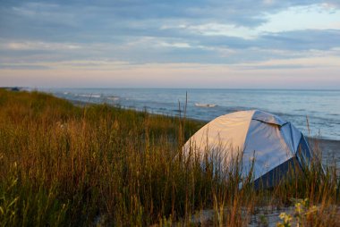 Camping tent on the beach in nature under the cloudy sky