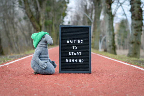 Игрушка Homunculus loxodontus сидит рядом с черным почтовым ящиком с надписью 'Waiting to start running'