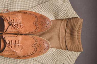 Kahverengi süet aksesuar ayakkabılar, açık bej ceket ve polo kazak.. 