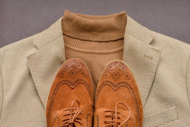 Kahverengi süet aksesuar ayakkabılar, açık bej ceket ve polo kazak.. 