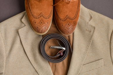 Bej ceket arka planında kahverengi süet derbi ayakkabısı. Üst görünüm.