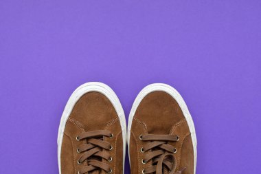 Mor arka planda bir çift kahverengi süet spor ayakkabı. Üst Manzara. Boşluğu kopyala.
