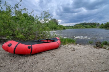 Nehir kıyısında dramatik gökyüzü olan kırmızı yük kamyonu. Seçici odaklanma. Etkin yaşam tarzı kavramı.