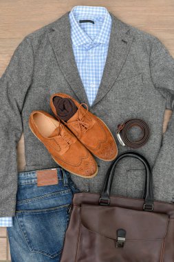 Bir çift kahverengi süet derbi ayakkabısı, mavi kot pantolon, deri kemer ve gri tüvit ceket. Sıradan bir iş görüşü. Üst görünüm.