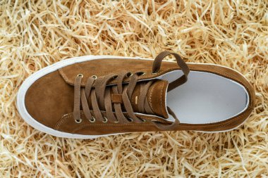 Top view brown suede sneaker on wood shavings background. 