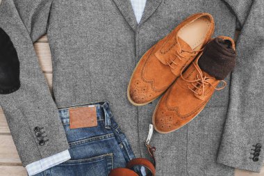 Bir çift kahverengi süet derbi ayakkabısı, mavi kot pantolon, deri kemer ve gri tüvit ceket. Sıradan bir iş görüşü. Üst görünüm.