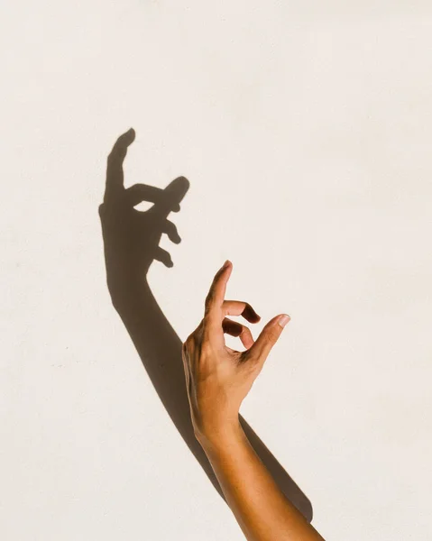 human hand shadow on vintage cream wall background.