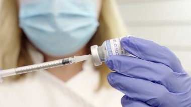 Coronavirus şişesi ve şırıngayla kadının yakın çekimi.