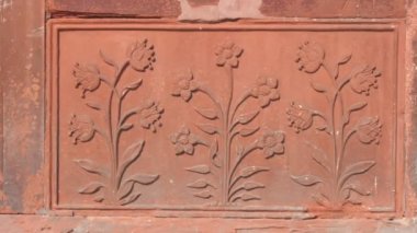 DELHI, INDIA - 15 Mart 2019: Eski Delhi 'deki kırmızı kalede taş bir duvara dekoratif çiçek oymacılığı - 4K 60p