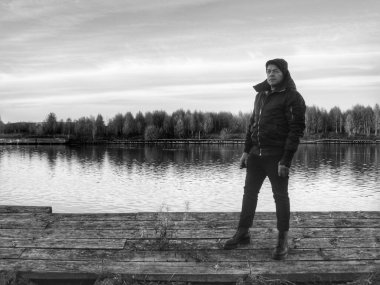 Göl kıyısında, gökyüzüne karşı duran bir adam.