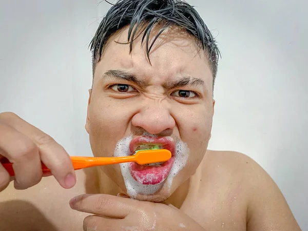 young man brushing teeth with foam