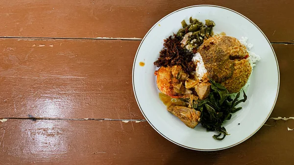 grilled padang chicken with vegetables and spices on a wooden background indonesian food