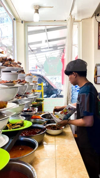 a cuisine photo of a padang restaurant and man taking food