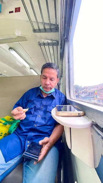 portrait of an old-haired man in a blue shirt is sitting in a train