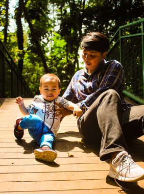 young boy and her father is playing with his baby son in the park. children play outdoors