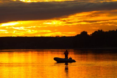 Gün batımında teknede balıkçıların silueti.
