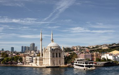 İstanbul 'daki tarihi Ortakoy camii Boğaz' da demirlemiş bir tur teknesinin görüntüsü. Güneşli bir yaz günü. Güzel seyahat sahnesi.