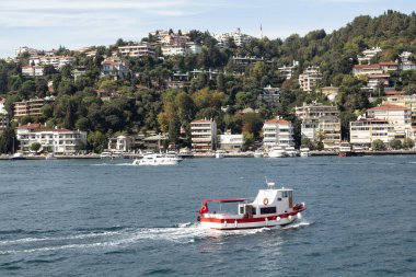 View of a fishing boat passing on Bosphorus and Bebek neighborhood on European side of Istanbul. It is a sunny summer day. Beautiful travel scene.