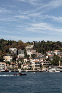 View of a fishing boat passing on Bosphorus and Bebek neighborhood on European side of Istanbul. It is a sunny summer day. Beautiful travel scene.
