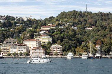 View of a yacht passing on Bosphorus and Bebek neighborhood on European side of Istanbul. It is a sunny summer day. Beautiful travel scene.