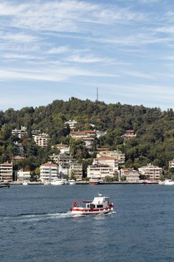 View of a fishing boat passing on Bosphorus and Bebek neighborhood on European side of Istanbul. It is a sunny summer day. Beautiful travel scene.