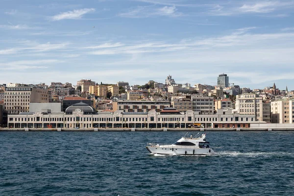 View of a yacht on Bosphorus passing in front of newly developed port in Istanbul. Beyoglu district is in the view. It is a sunny summer day.