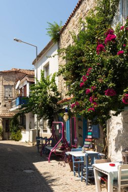 View of an old, historical, traditional stone houses and bougainvillea flowers in famous, touristic Aegean town called Alacati. It is a village of Cesme, Turkey. It is a sunny summer day