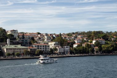 View of a yacht passing on Bosphorus and Baltalimani neighborhood on European side of Istanbul. It is a sunny summer day. Beautiful travel scene.