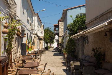 View of cafes and old, historical, traditional stone houses in famous, touristic Aegean town called Alacati. It is a village of Cesme, Turkey. It is a sunny summer day