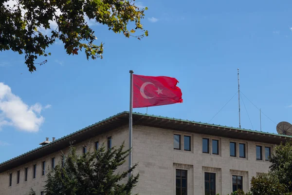 View of Turkish flag waving in front of state owned radio's building by one of the main avenues called Halaskargazi in Sisli district of Istanbul. It is a sunny summer day.