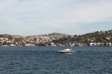 View of a yacht passing on Bosphorus and Asian side of Istanbul. It is a sunny summer day. Beautiful travel scene.
