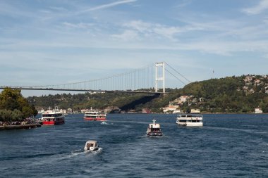 View of cruise tour boats passing on Bosphorus and FSM bridge in Istanbul. It is a sunny summer day. Beautiful travel scene.