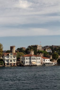 View of historical, traditional mansions and old Anatolian fortress by Bosphorus in Anadolu Hisari area of Asian side of Istanbul. It is a sunny summer day. Beautiful travel scene.