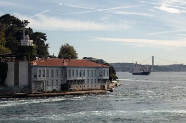 İstanbul 'un Asya yakasının Kandilli bölgesindeki İstanbul Boğazı' nın tarihi köşkü. Kuru kargo gemisi ve Boğaz köprüsü arka planda. Güneşli bir yaz günü..