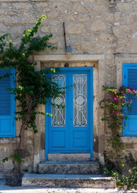 View of old, historical, traditional stone house with blue colored door and windows in famous, touristic Aegean town called Alacati. It is a village of Cesme, Turkey. It is a sunny summer day