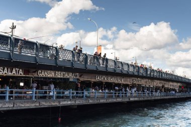 Galata Köprüsü 'ndeki balıkçılar ve İstanbul' daki balık restoranlarının manzarası. Görüntü, yerel halkın yaşam tarzını ve kültürünü yansıtıyor. Güneşli bir yaz günü..