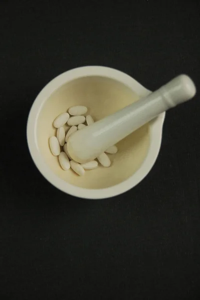 pestle with pills on a black background
