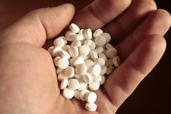 white pills poured into a handful