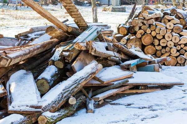 Stacked wood covered with snow. Background. A woodpile of dry fire woods in the winter. Stack of fire wood with snow. Winter fire wood provisions. Row of fire wood stock for winter. Winter..