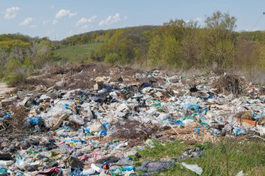 Çöp sahasının manzarası. Çöp yığını. Bir yığın plastik çöp, yiyecek atıkları ve diğer çöpler. Kirlilik konsepti. Bir çöp denizi, güzel bir kırsal alanı istila etmeye ve yok etmeye başlar..