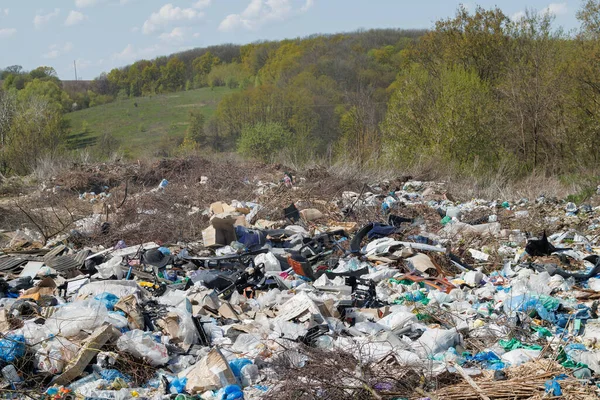 A view of the landfill. Garbage dump. A pile of plastic rubbish, food waste and other rubbish. Pollution concept. A sea of garbage starts to invade and destroy a beautiful countryside scenery.