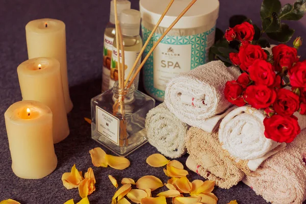 Towels with dried flowers and candles for a relaxing spa massage and body care. Composition with almond oil, massage cream