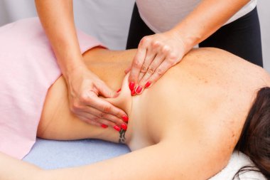 relaxed young woman lying face down on massage table enjoying therapeutic body massage by professional masseur in spa or wellness center.
