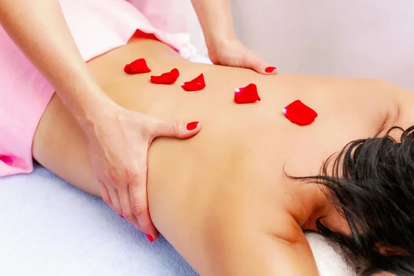 Young woman getting a massage at the spa. A woman enjoys a relaxing back massage in a beauty spa. Body care, skin care.