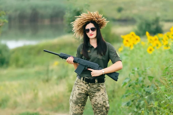 Female soldier in military uniform. A girl in a military uniform with a weapon. Ukrainian woman in a wreath.