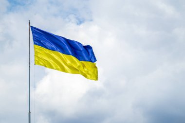 A damaged flag of Ukraine flies against the background of a cloudy sky
