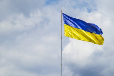 A damaged flag of Ukraine flies against the background of a cloudy sky