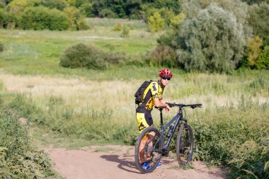 Genç bayan bisikletçi yaz ormanı patikasında güneşin doğuşunun tadını çıkarıyor..