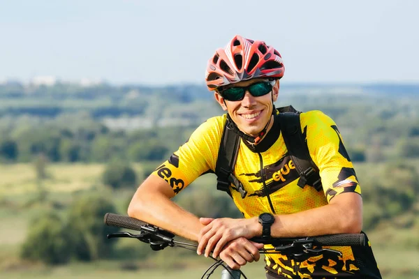 A cyclist in sportswear poses with his mountain bike.