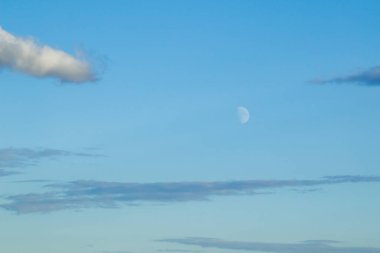The moon and clouds in the blue evening sky. Natural background photo texture.